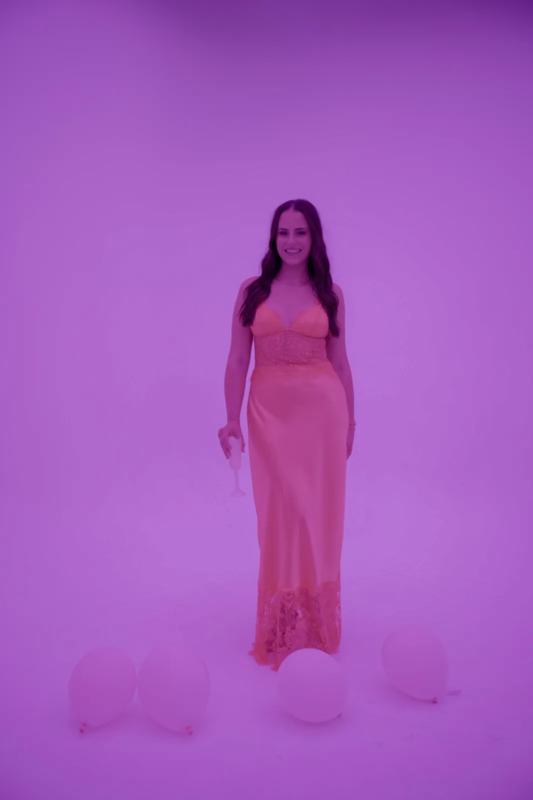 A guest in a pink dress lit by pink studio light