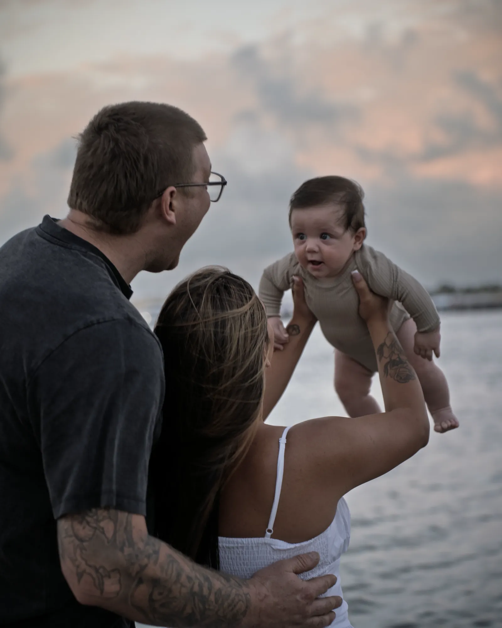 Parents lifting their baby up between them on the beach
