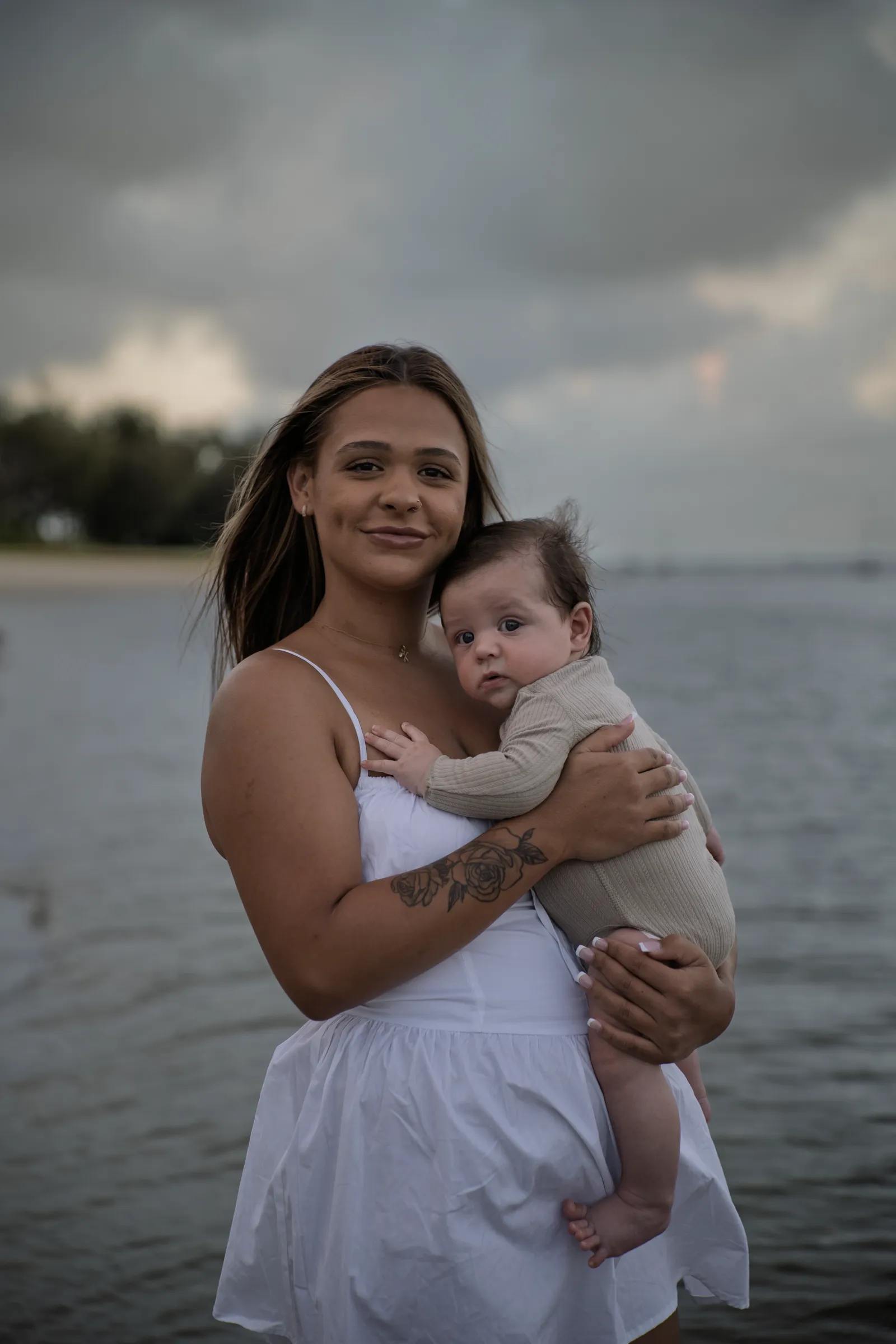 A mother holding her baby on the sand at sunset