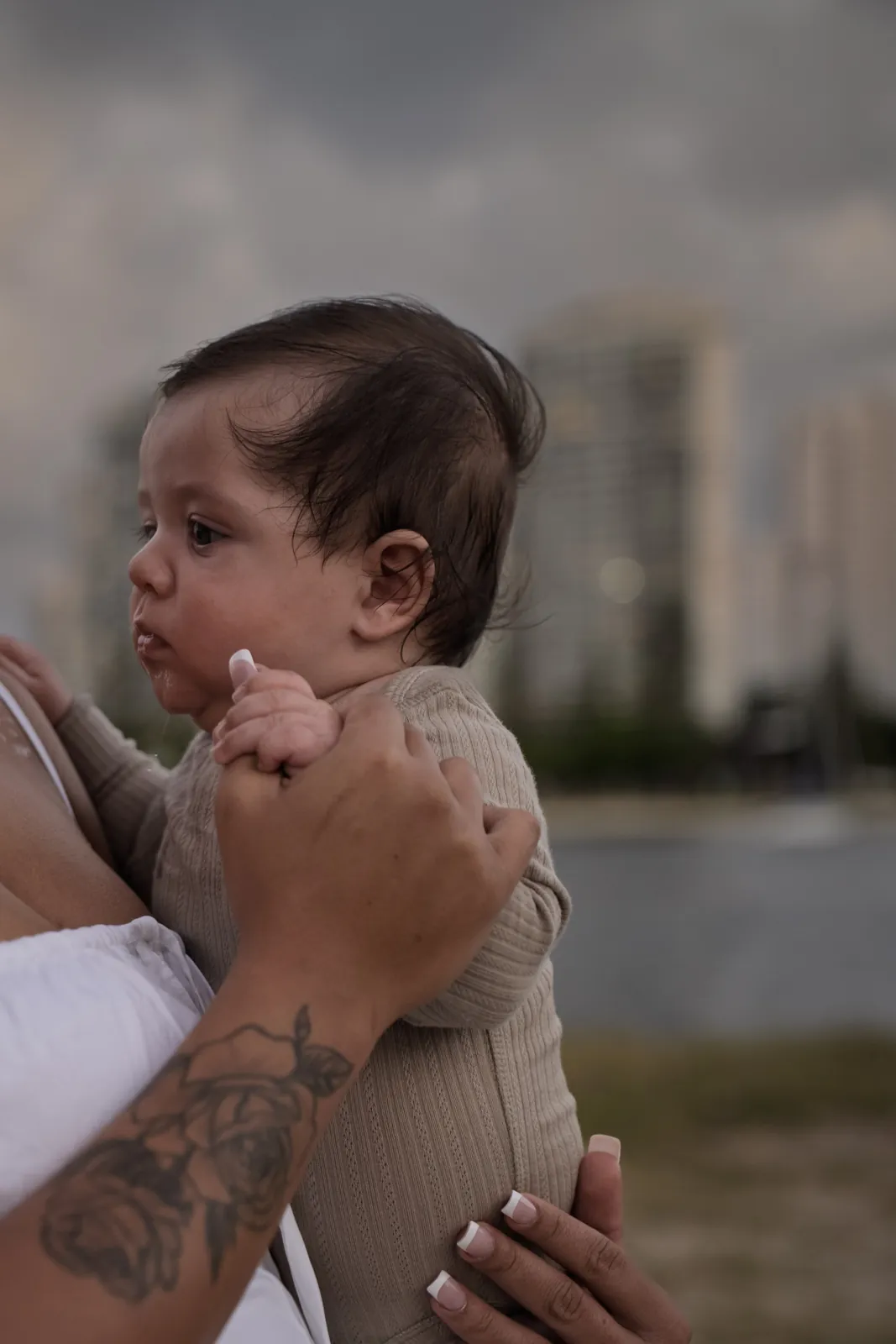 A baby looking back over a shoulder at the beach