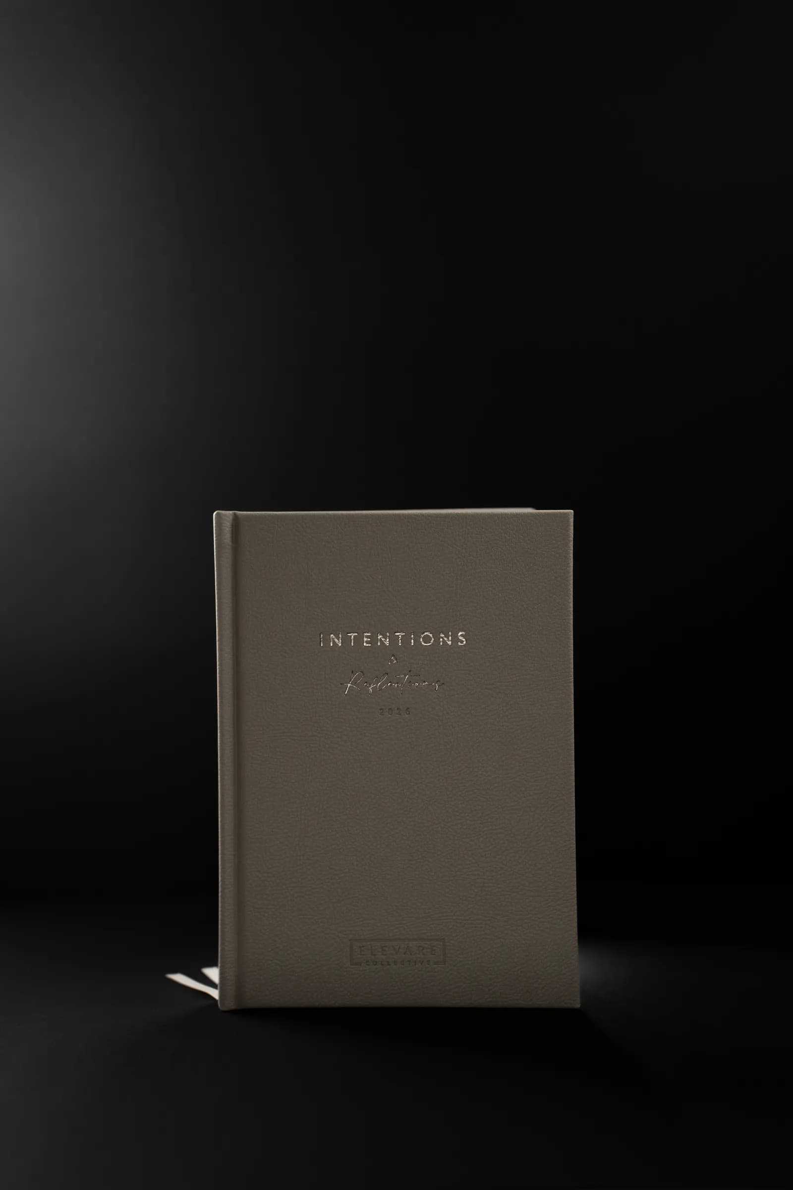 A taupe Intentions journal standing on a black background