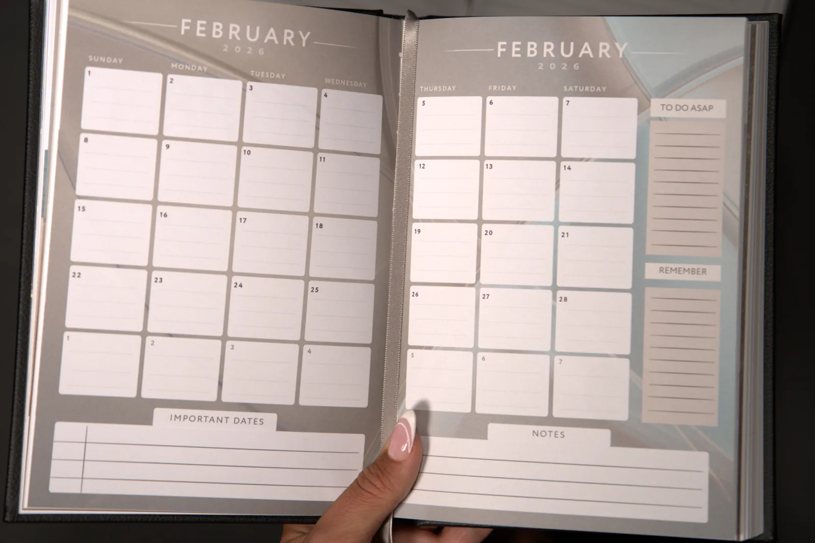 Hands holding the journal open at the February calendar spread