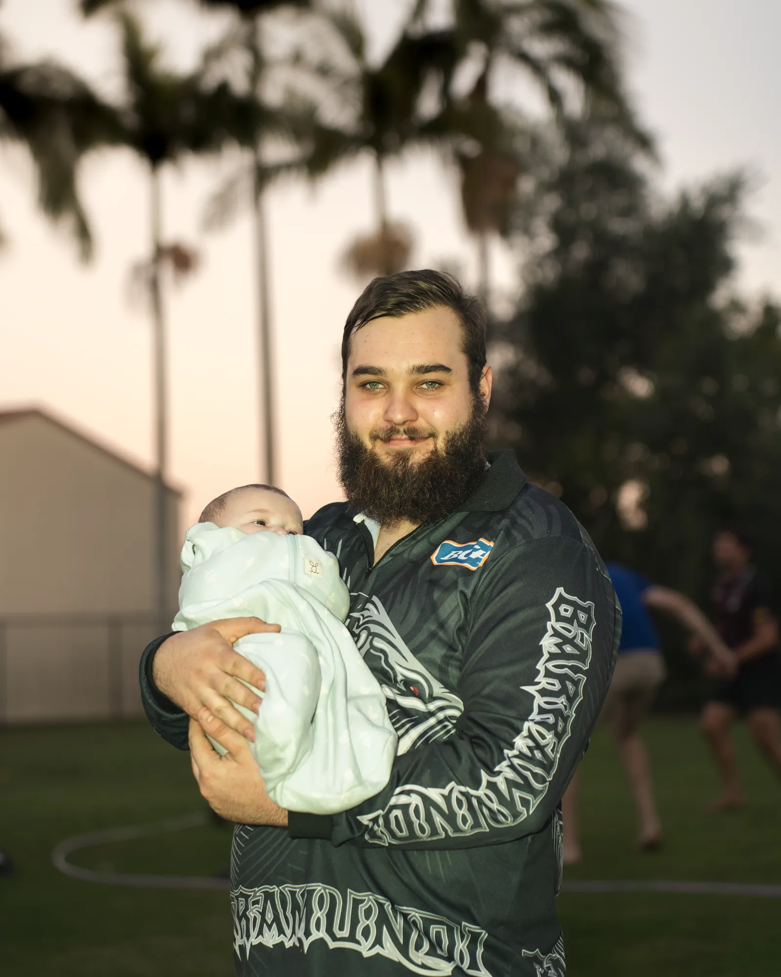 A guest holding a newborn at the baby shower, sunset behind